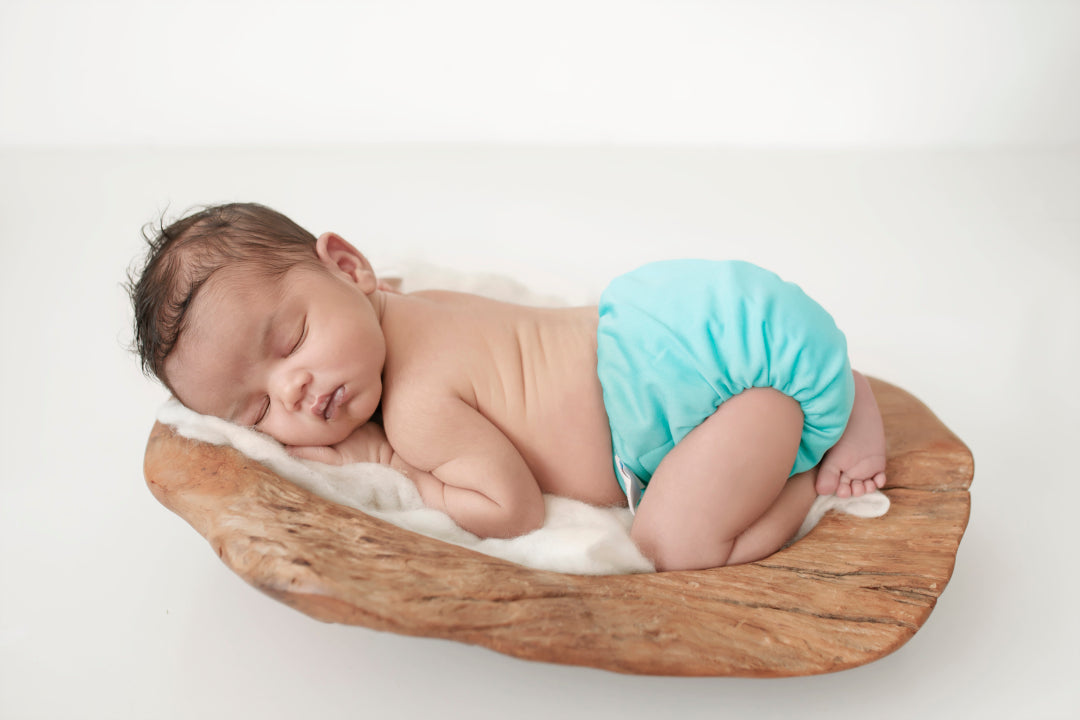 3kg baby sleeping on a log wearing a blue cloth nappy. The cloth nappy fits nicely on any size baby. from 3 kg to over 15kg