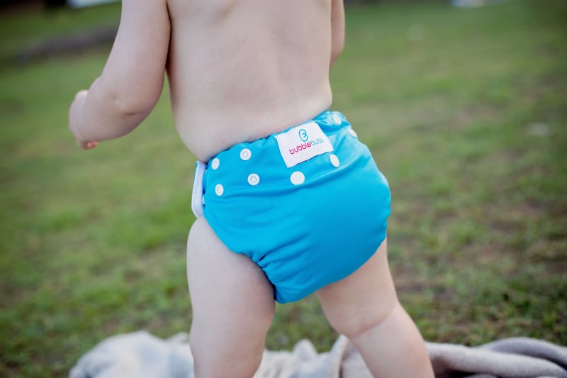 Toddler running in a blue Bubblebubs Candie cloth nappy. You can see the reusable nappy is handling the job with style.