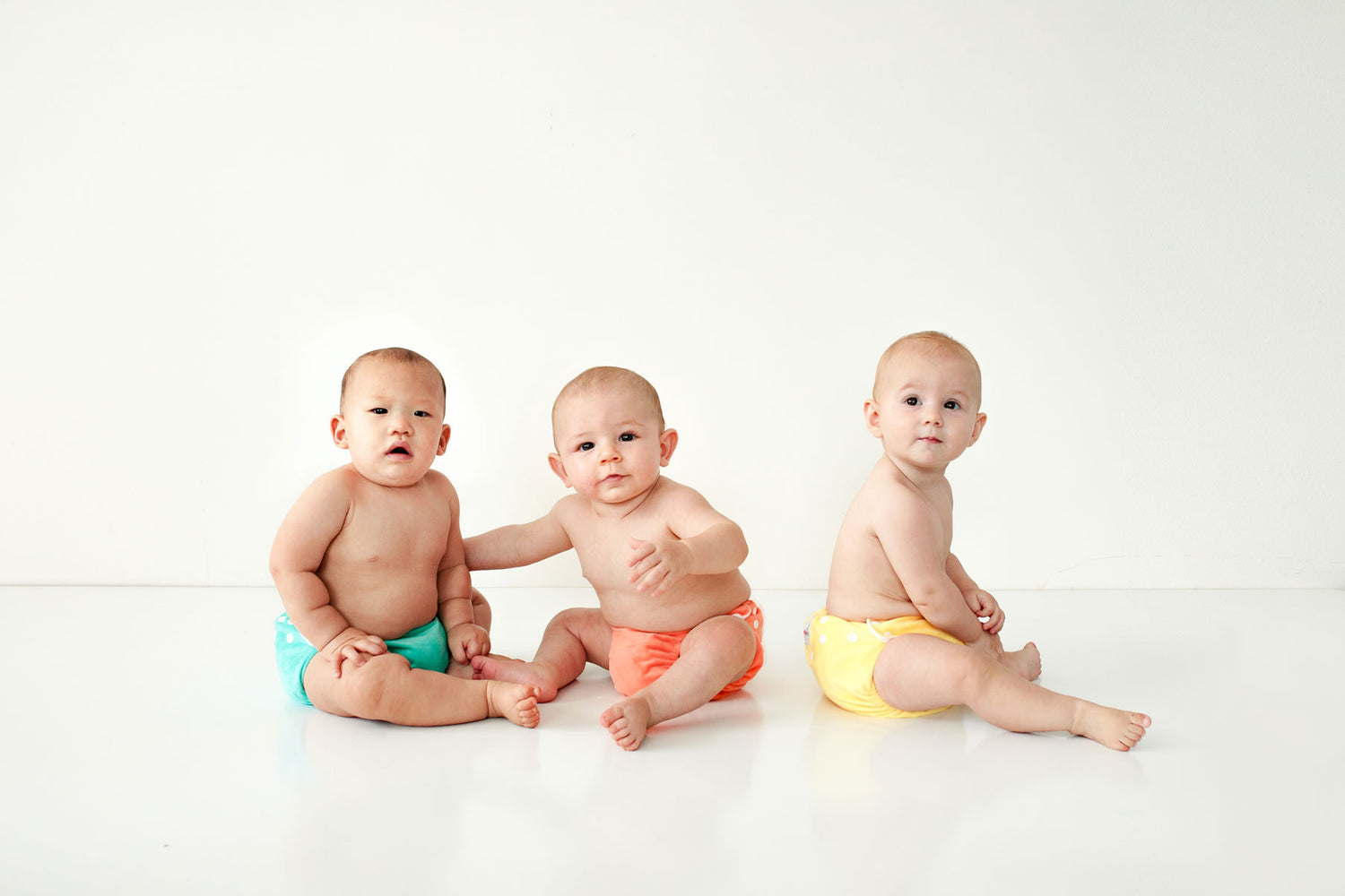 three babies all in cloth nappies green orange and yellow